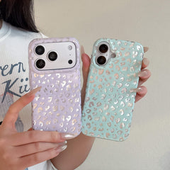 Close-up of a person holding pastel purple and mint green metallic leopard print phone cases.
