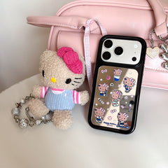 A silver Hello Kitty mirror iPhone case displayed on a white table next to a matching plush doll and a pastel pink handbag.