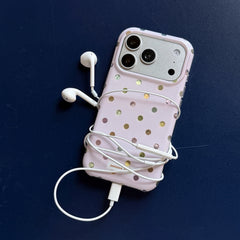 A holographic polka dot iPhone case wrapped in white headphone cords over a dark blue background.