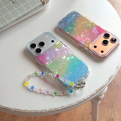 Two holographic shell texture gradient phone cases with reflective metallic lens bumpers displayed on a white round side table.
