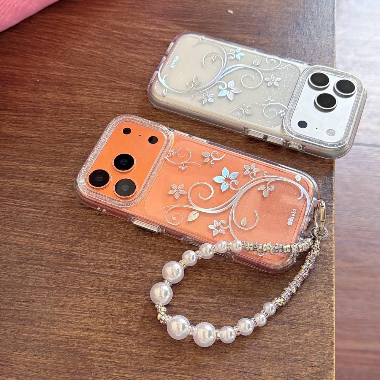 Two iridescent floral vine iPhone cases with clear bumper and pearl strap