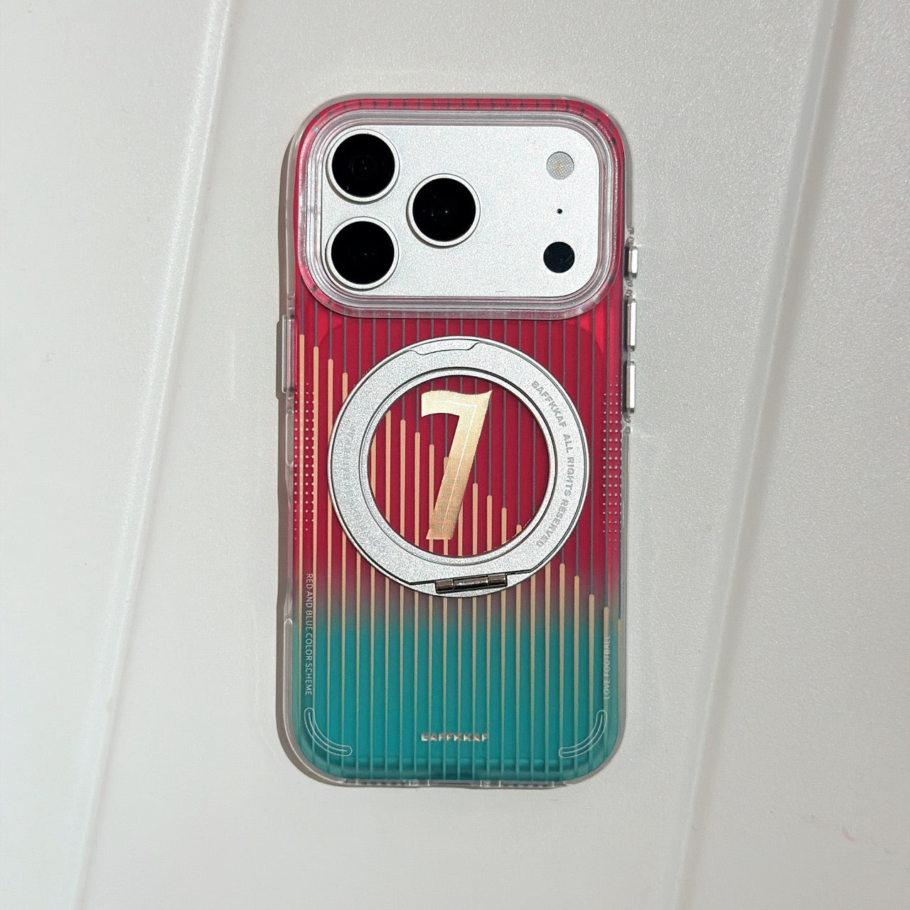 Product photography of a clear magnetic iphone case featuring a vertical red to green gradient pattern, a gold number 7, and a flush silver MagSafe ring holder on a plain white background.