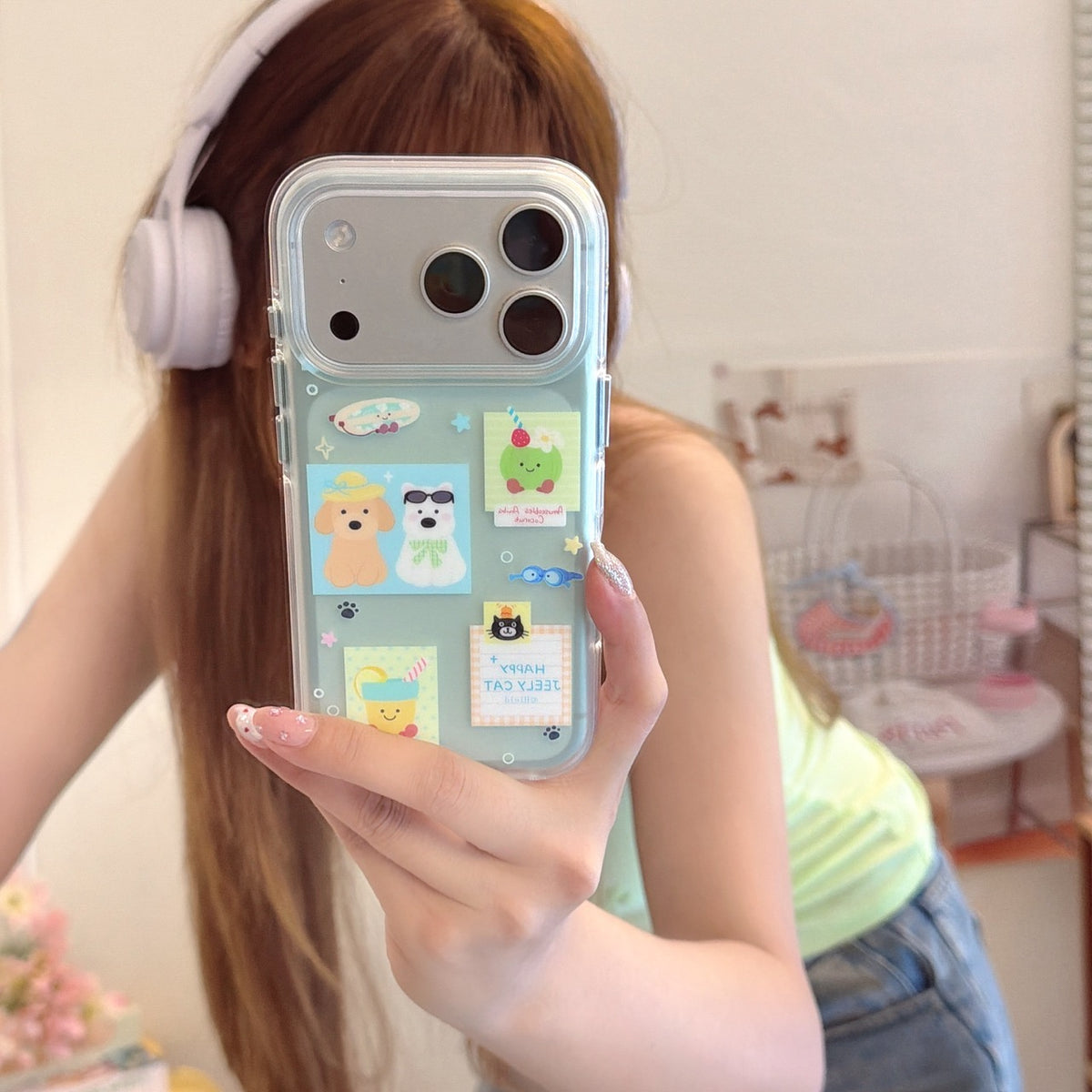 A girl taking a mirror selfie with a mint green iPhone case featuring cute cartoon dog and cat stickers.