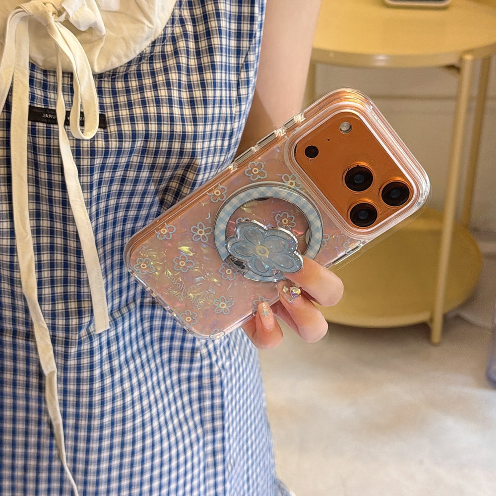A girl holding an orange iPhone protected by a shimmering floral pearl case with a blue flower phone grip.