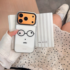A girl displaying a kawaii glasses face phone case with an orange lens frame on a book.