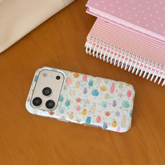 Flatlay view of a kawaii ocean fish clear iPhone case with a silver camera protector on a wooden desk near notebooks.
