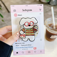 Hand holding a clear kawaii pet iPhone case with colorful cartoon puppy artwork.