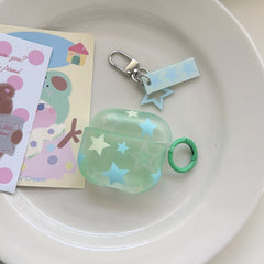 A translucent mint green AirPods case decorated with pastel stars and a matching star charm keychain on a white ceramic plate.