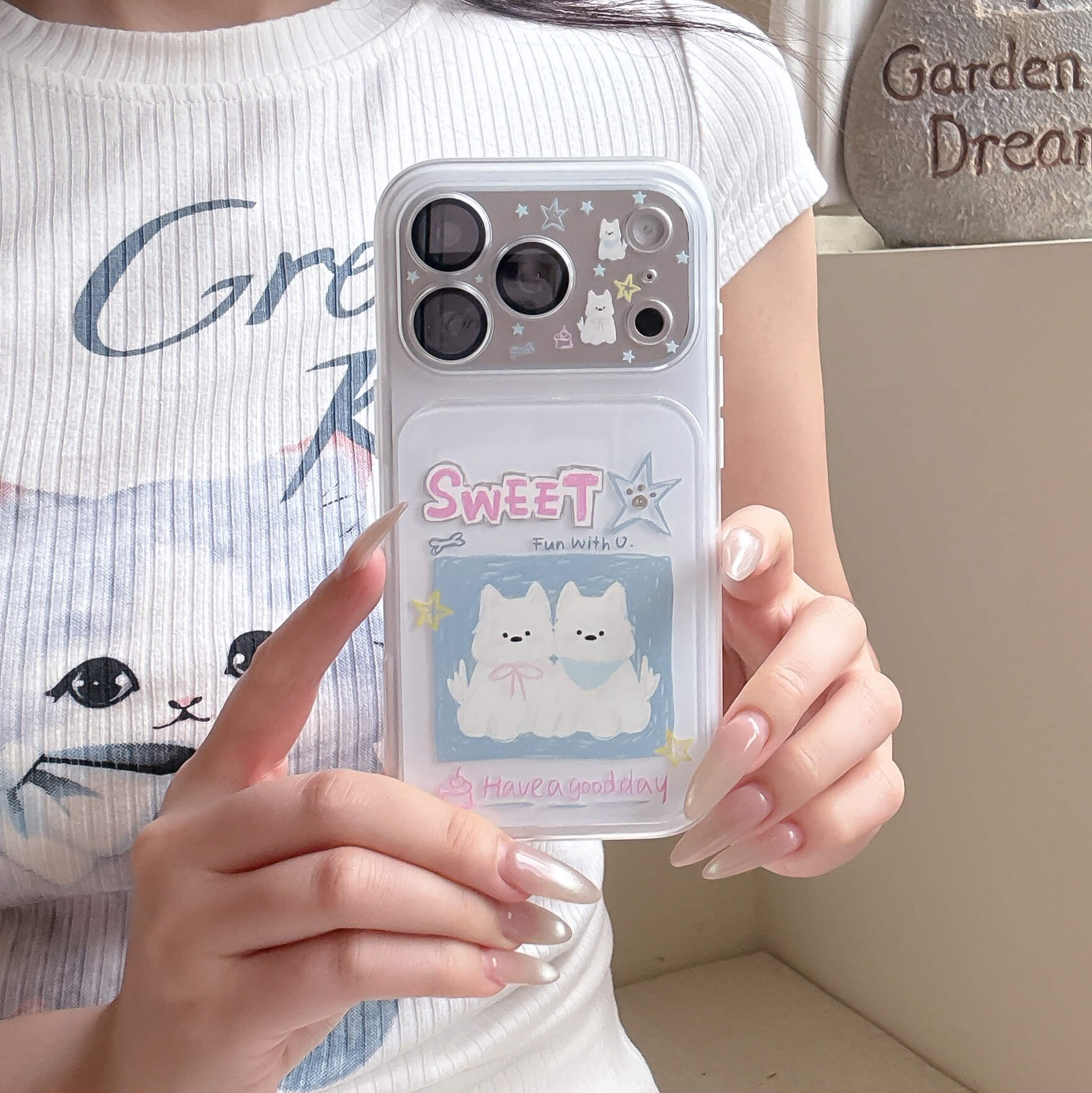 A girl holding a clear shockproof phone case with kawaii white puppy prints over a casual graphic tee.