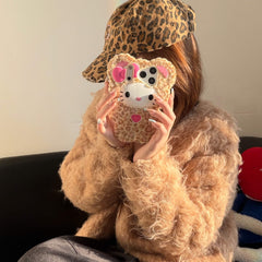 Woman styling a leopard kitty plush iPhone case with a leopard-print cap