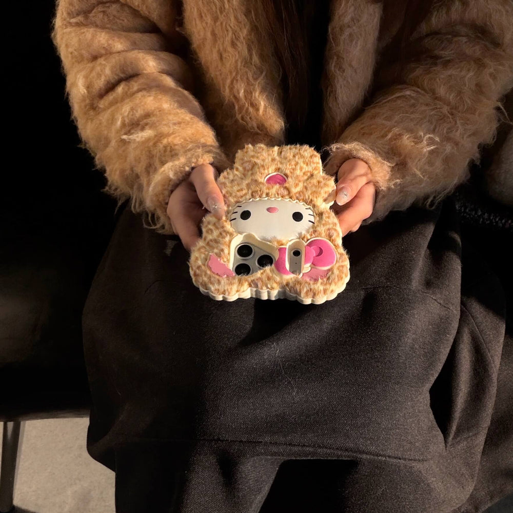 Close-up of a leopard kitty plush iPhone case held on a lap in sunlight