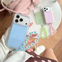 Top-down view of a hand holding a light blue matte phone case with a blue beaded charm over a polka dot dress.