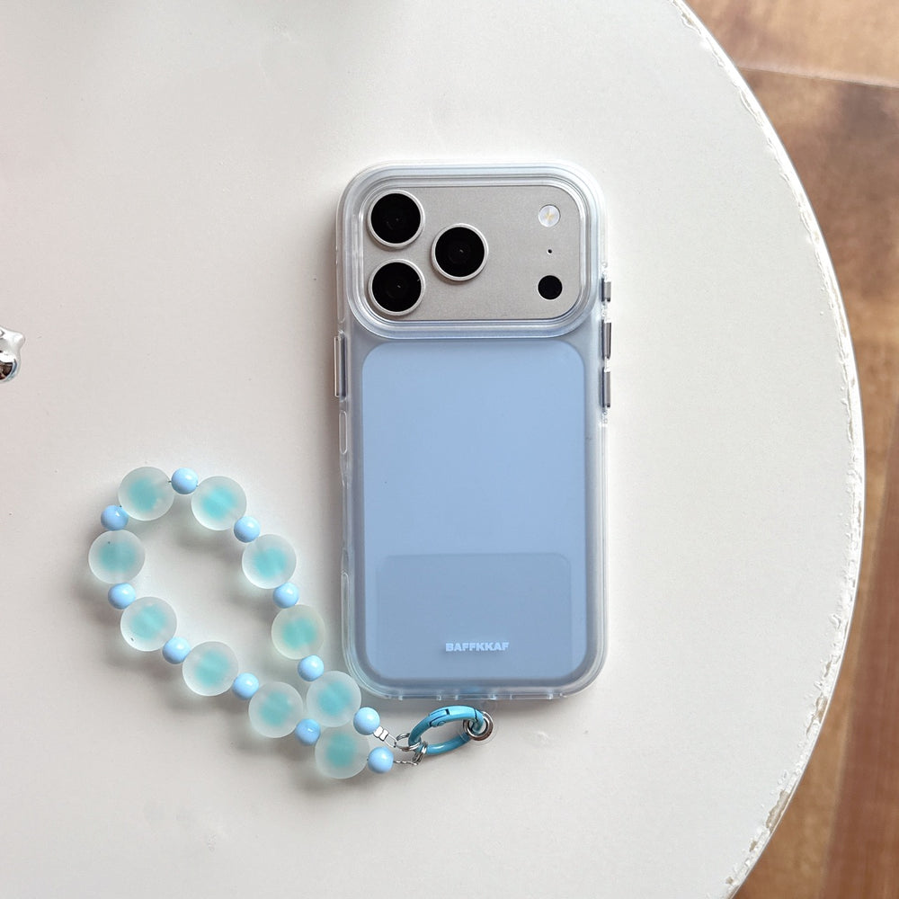 Light blue pastel phone case with a clear shockproof bumper and a blue frosted beaded wrist strap on a white table.