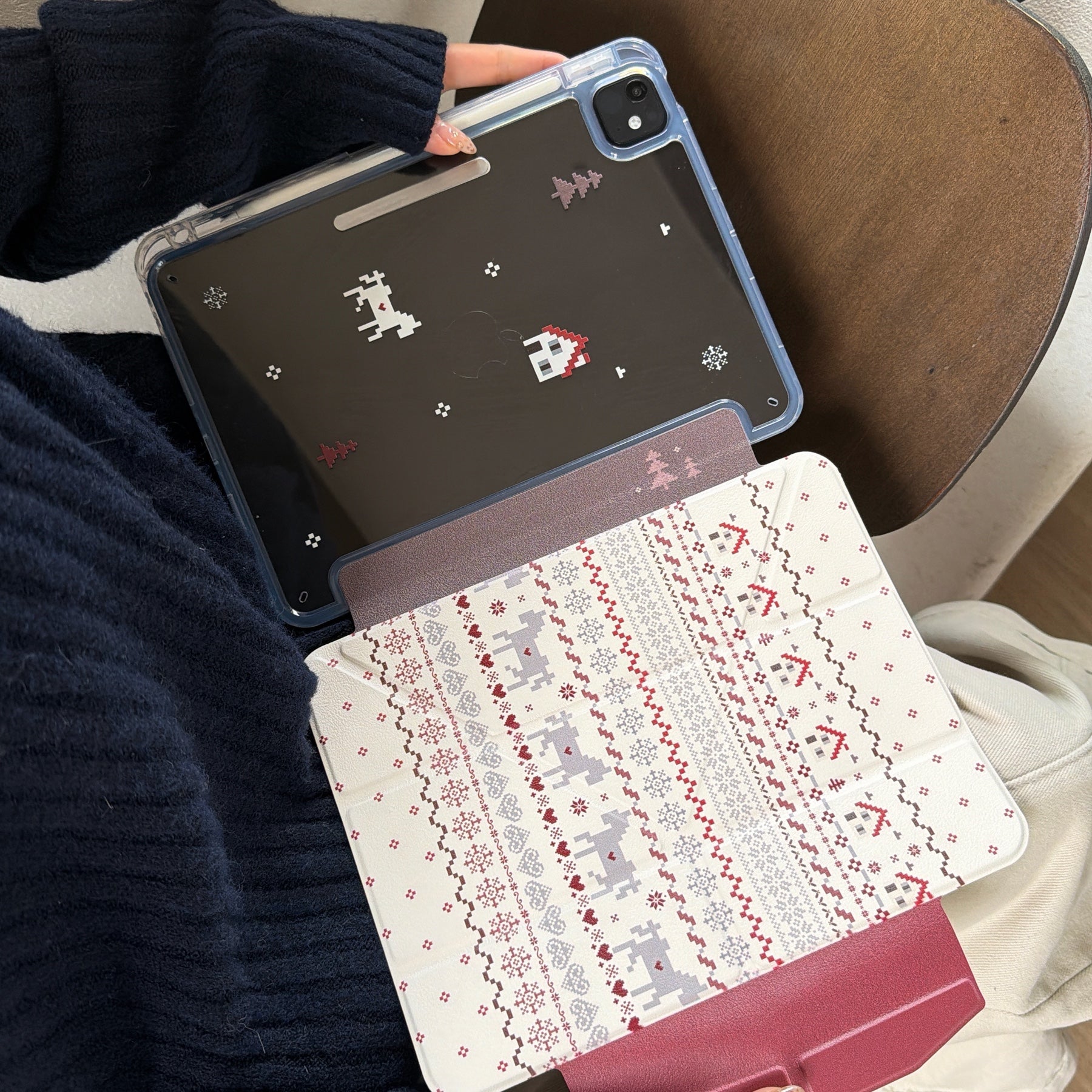 An iPad case demonstrating its 2-in-1 magnetic detachable folio feature where the clear back panel splits away from the cream Fair Isle patterned smart cover.