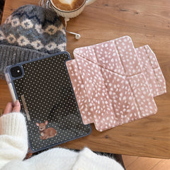 A cozy flat lay on a wooden table featuring a magnetic detachable vintage fawn iPad case separated into its polka dot back shell and deer-print origami folio, beside a warm latte and a knit beanie.