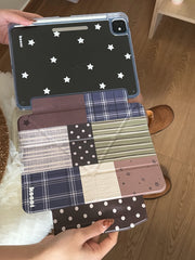 A top-down view of the magnetic detachable iPad case opened flat on a lap, showcasing the clear back panel with white stars separating from the multi-patterned cottagecore folio cover.