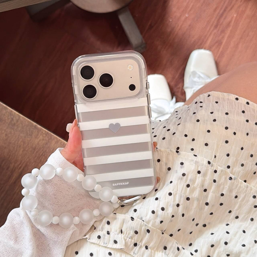 Hand holding minimalist gray heart iPhone case with white bead strap