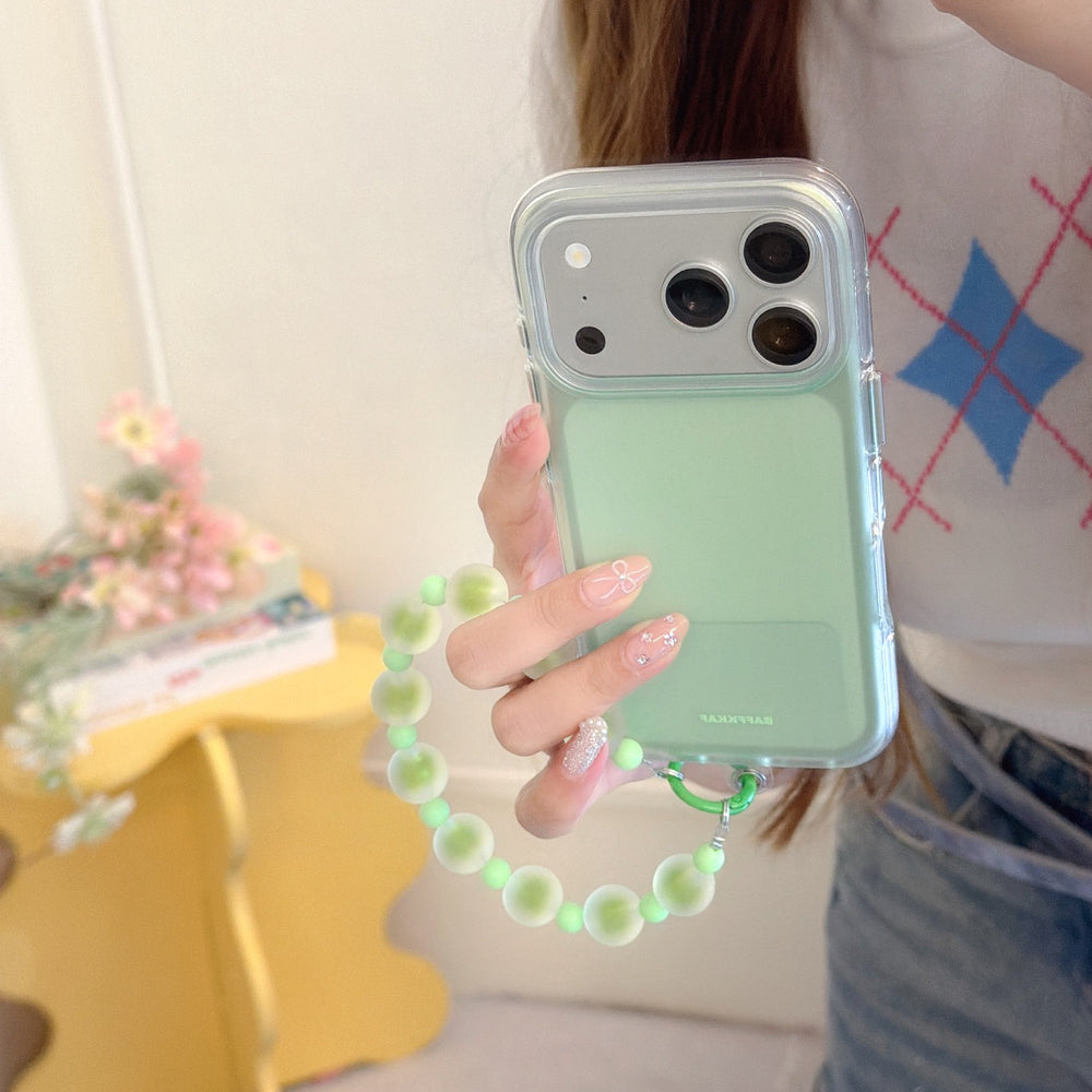 Close-up of a hand with manicured nails holding a mint green aesthetic iPhone case with a green frosted bead wrist strap.