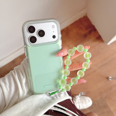 Close-up of a mint green BAFFKKAF phone case with a shockproof clear bumper and a green beaded bracelet holder.