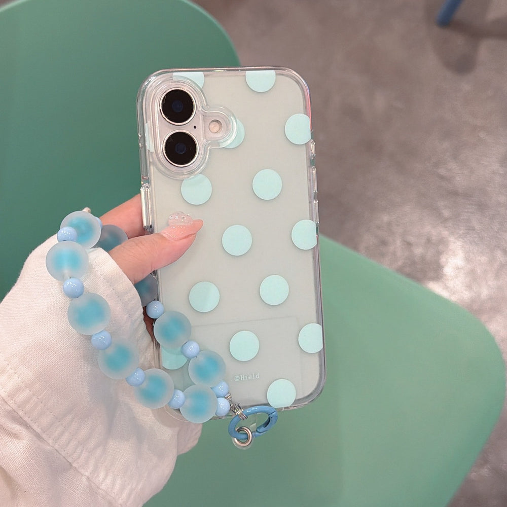 Close-up of a mint green polka dot iPhone case with a pastel blue jelly beaded charm strap.