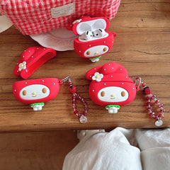 Multiple cute silicone cartoon earphone cases and red crystal strawberry charms displayed on a wooden surface.