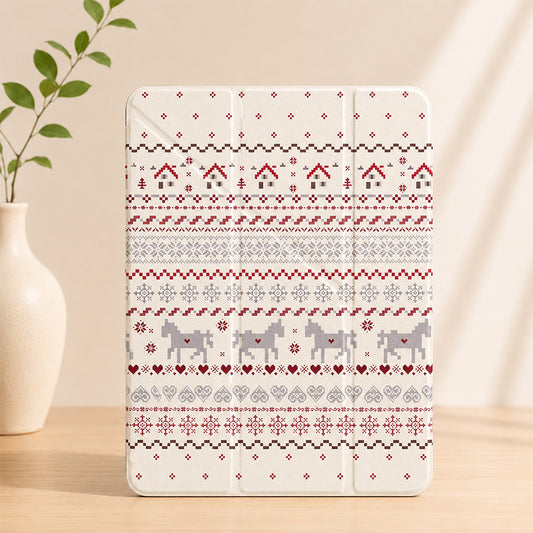A closed cream-colored Nordic Fair Isle pattern iPad case standing upright on a light wooden table next to a white ceramic vase with green leaves.