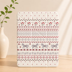 A closed cream-colored Nordic Fair Isle pattern iPad case standing upright on a light wooden table next to a white ceramic vase with green leaves.
