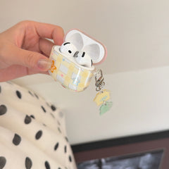 A hand holding an open clear kawaii gingham AirPods case filled with wireless earbuds.