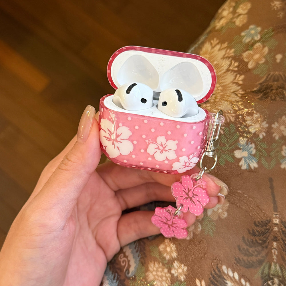 A hand holding an open translucent pink polka dot AirPods case showing white earbuds inside.