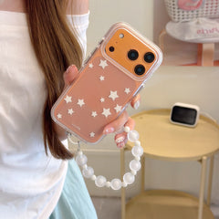 A hand holding an orange clear iPhone case featuring white star graphics and a glossy metallic camera frame.