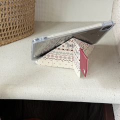 An iPad propped horizontally using an origami folding stand case on a white textured ledge with a woven rattan basket in the background.