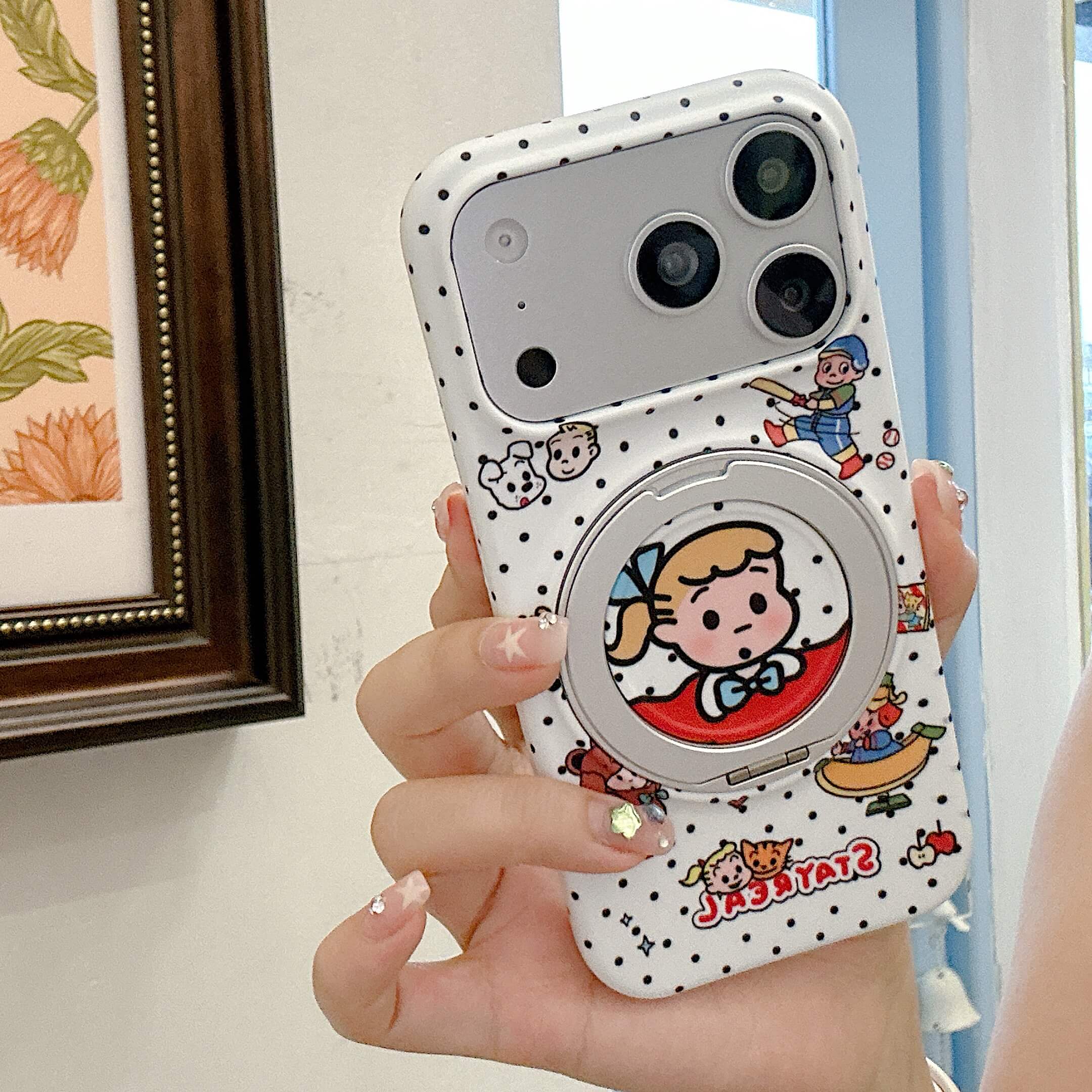 Hand holding the white polka dot phone case vertically with retro Japanese cartoon graphics visible.