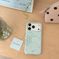 Top-down view of a pastel blue polka dot iPhone case on a wooden table next to a small makeup pouch.