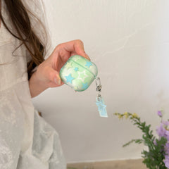 A hand holding a pastel green star AirPods case featuring an attached silver lobster clasp and star pendant.