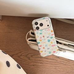 A pastel marine life clear iPhone case leaning against a stylish white leather handbag on wooden flooring.