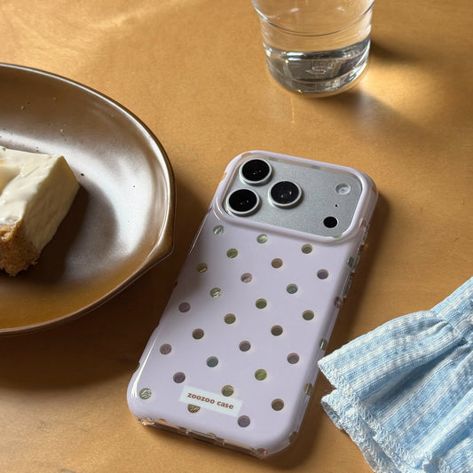 A pastel purple holographic polka dot iPhone case on a wooden table next to a plate of cake.