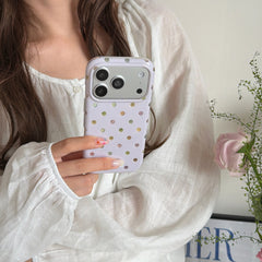 A close-up of a woman in a white blouse holding a pastel purple polka dot iPhone case.