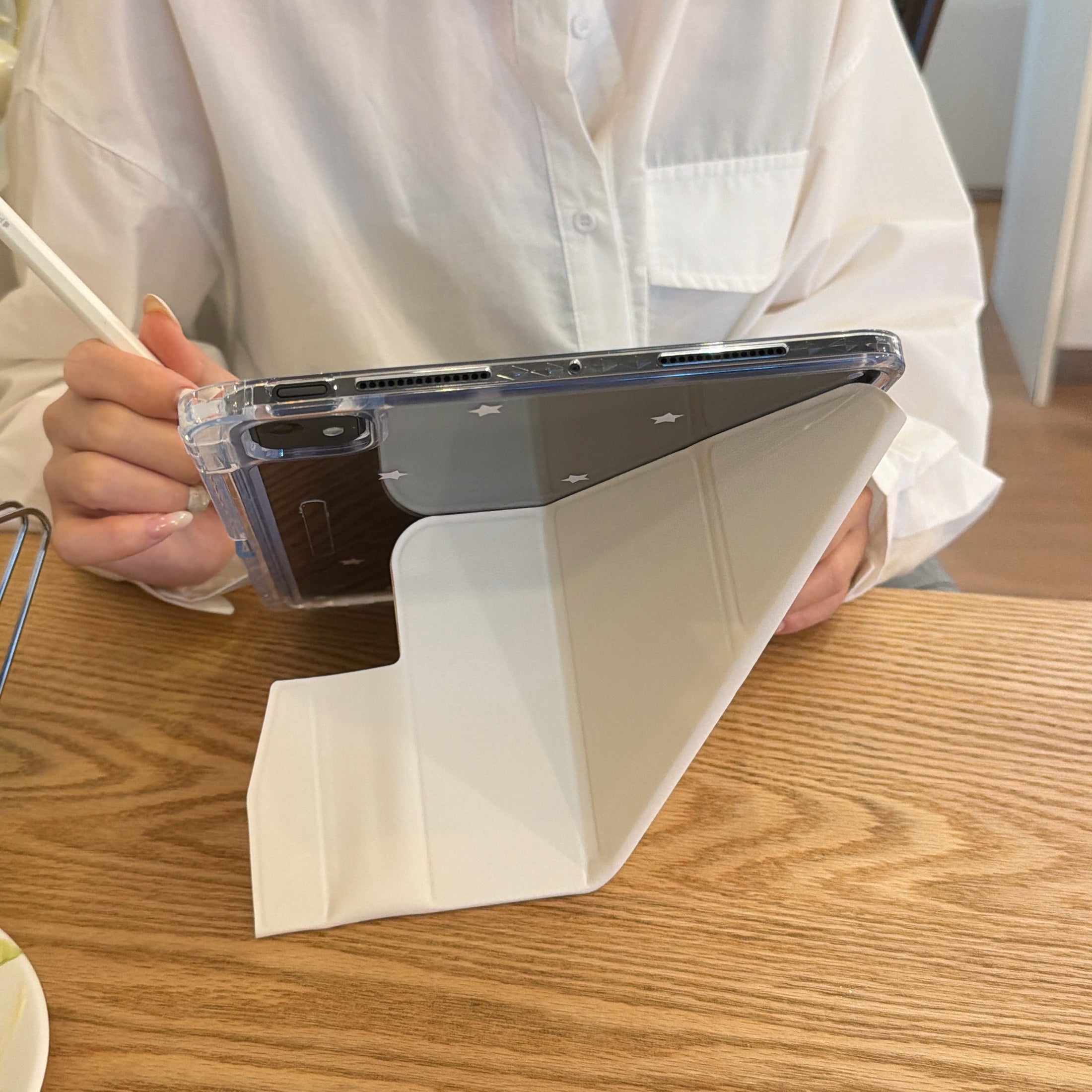 Rear view of a black iPad supported by a folded pastel rocking horse smart ipad case, showing the clean white interior lining of the stand.