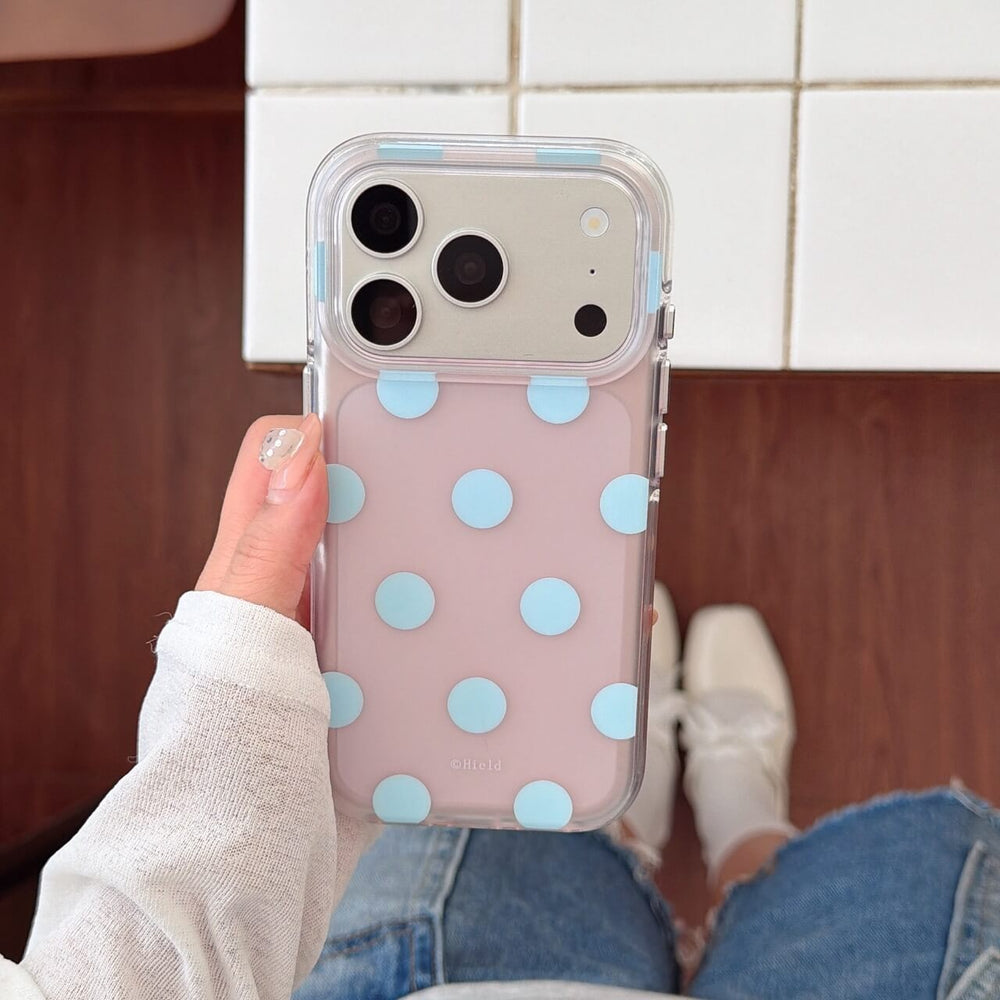 Pink clear iPhone case with raised blue polka dots held by hand
