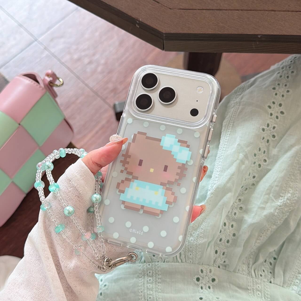 Hand holding a clear pixel kitty iPhone case with blue bow artwork