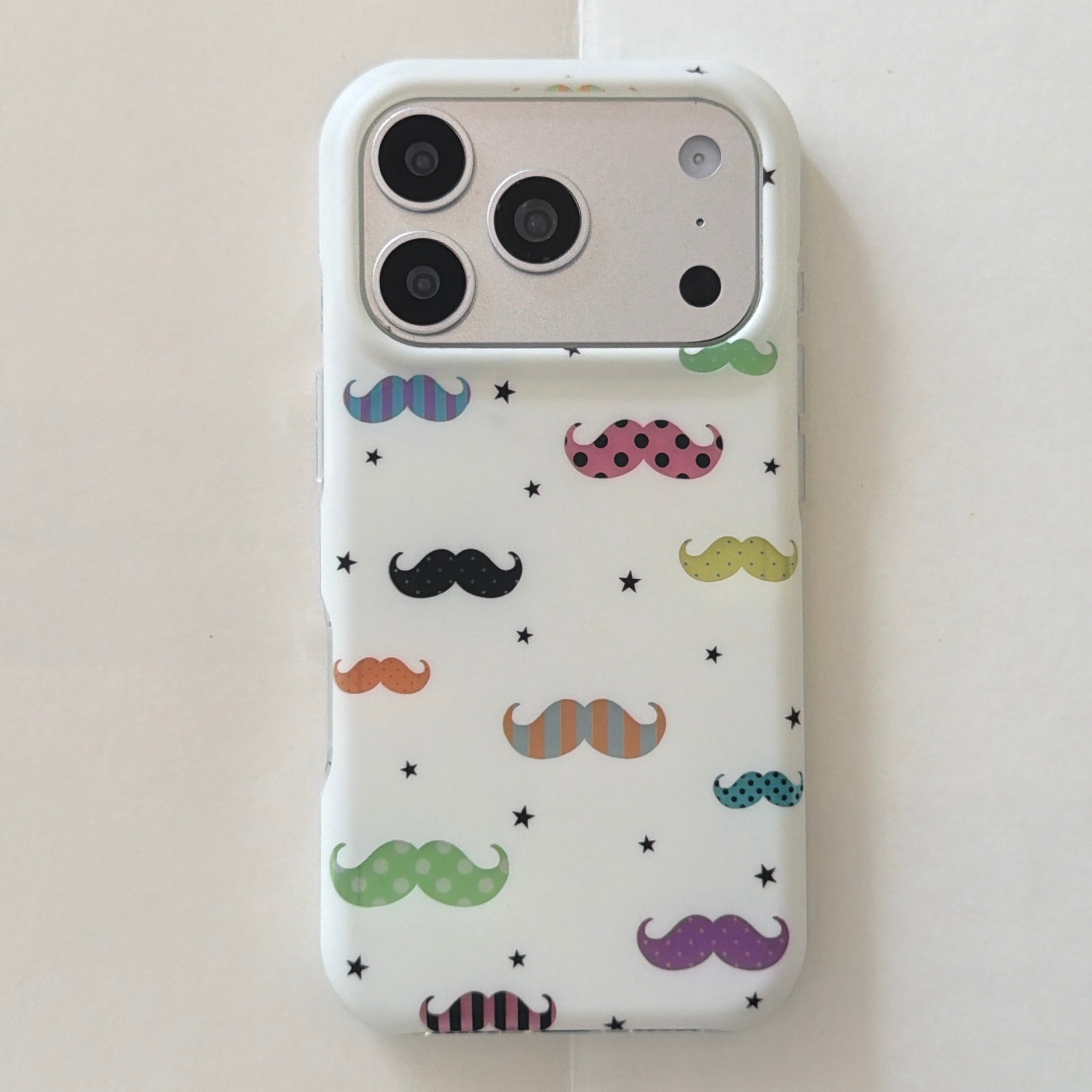 A flat lay view of a white iPhone case featuring a colorful mustache and star pattern.