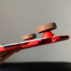 Close-up side view of a red silicone bus iPad case, showing the precise speaker and charging port cutouts on the bottom edge and the side profile of two thick brown wheel kickstands.