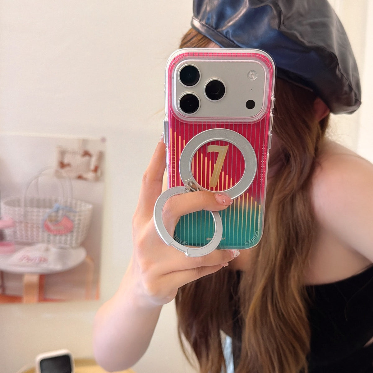 A girl wearing a black leather beret takes a mirror selfie to show off a sports-style gradient phone case with a built-in magnetic ring holder.
