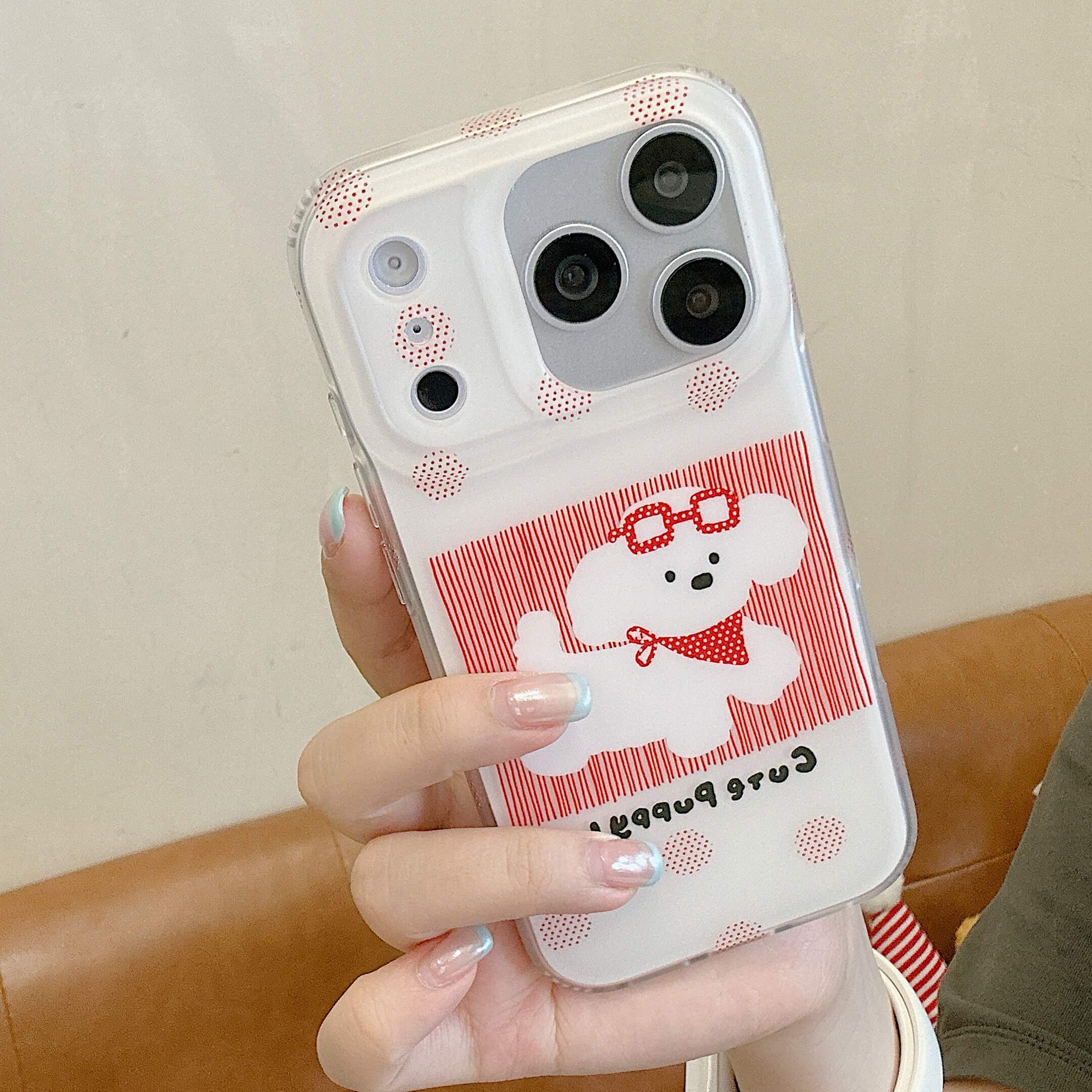 Hand holding a red puppy iPhone case with polka dot accents.