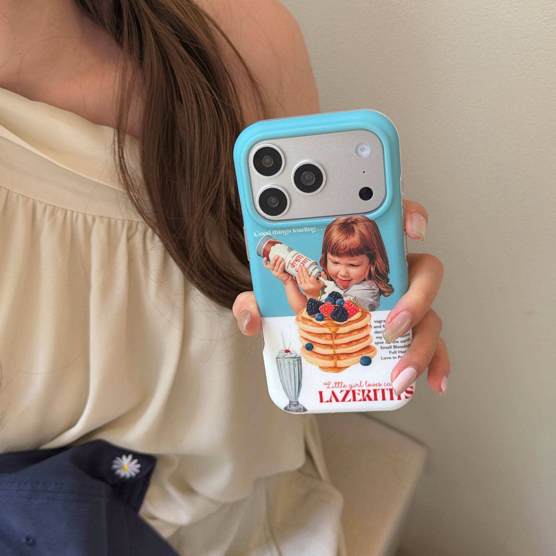 A woman wearing a cream dress holding a retro aesthetic girl pancake iPhone cover.