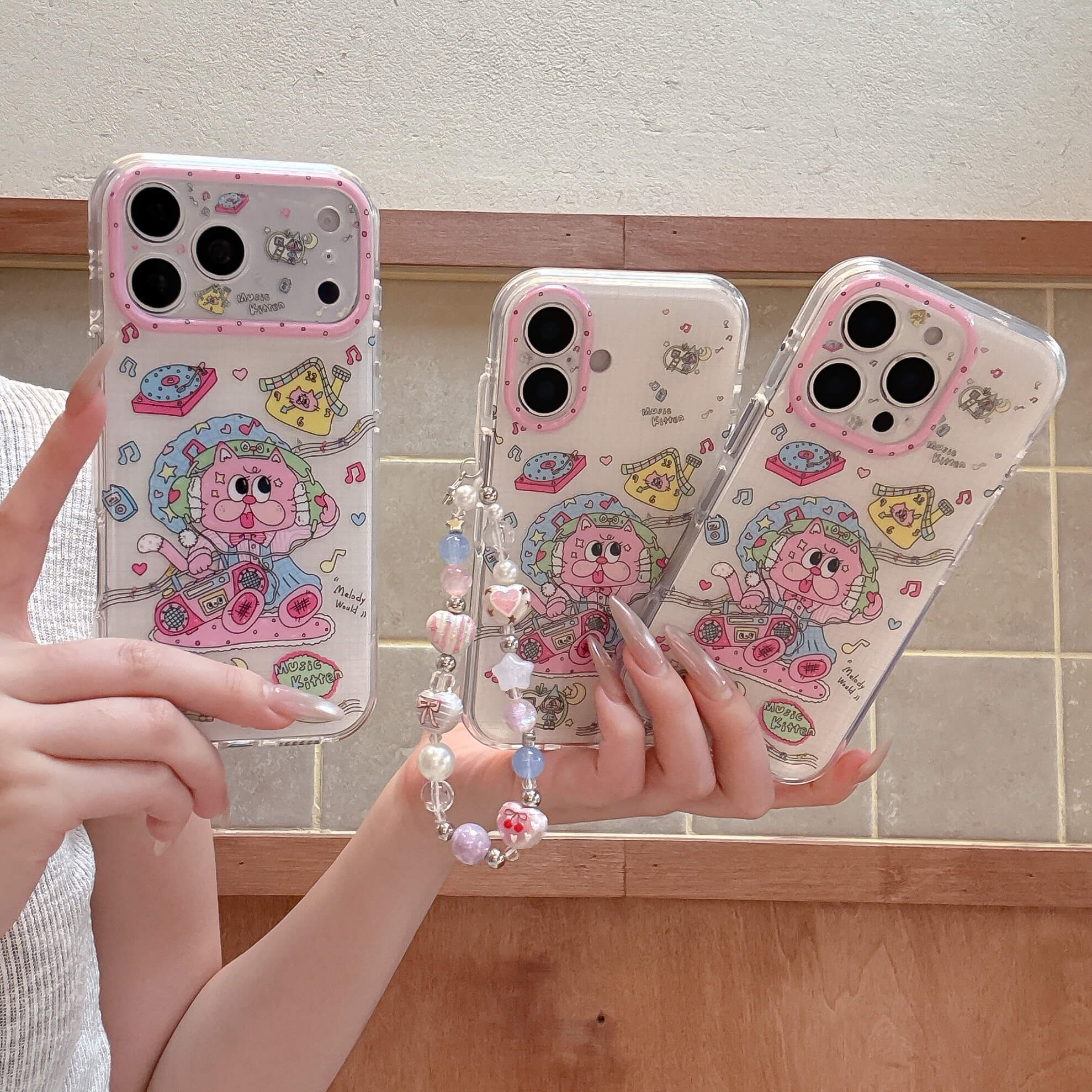 A person holding three retro cartoon cat phone cases showing different iPhone model fits.