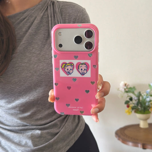 A woman's hand holding a retro cartoon pink iPhone case showing the holographic heart patterns.