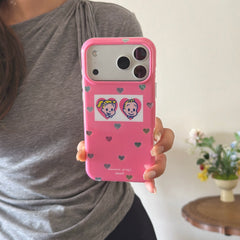 A woman's hand holding a retro cartoon pink iPhone case showing the holographic heart patterns.