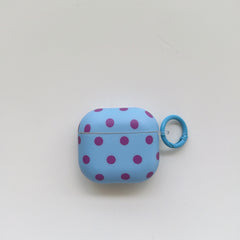 Front view of a light blue AirPods case with purple polka dots and a matching circular clip ring on a plain white background.