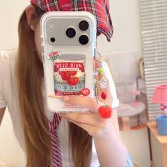 A girl taking a mirror selfie holding a retro tomato can iPhone case with a cute tomato charm lanyard.